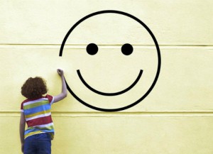 Girl drawing smiley face on to a wall
